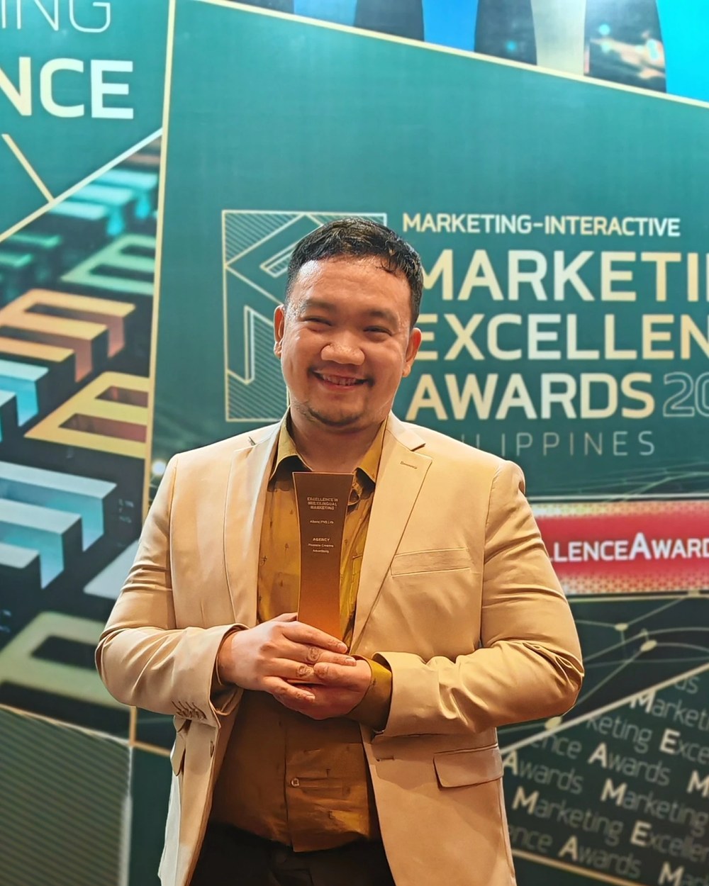 Jom Lirios holding the Marketing Excellence Awards 2025 Gold trophy for Excellence in Multilingual Marketing